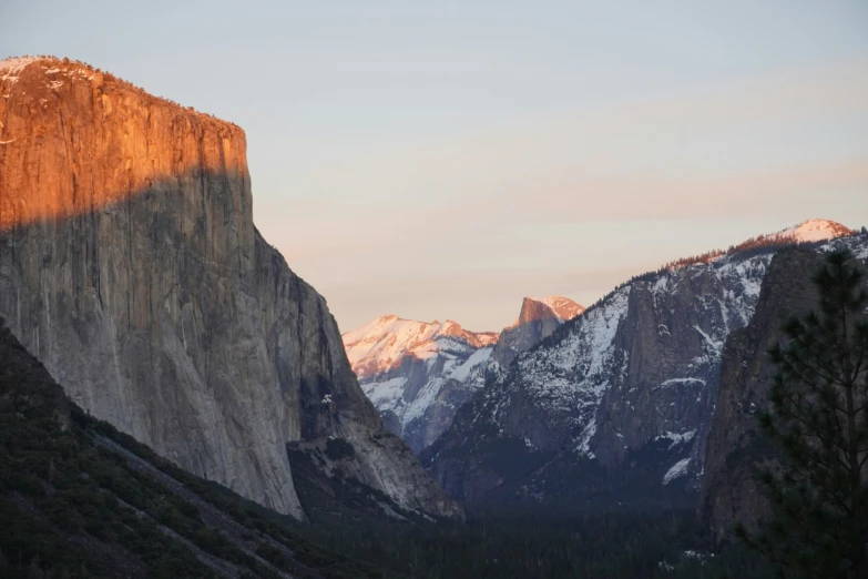 a large mountain with a few trees on the ground