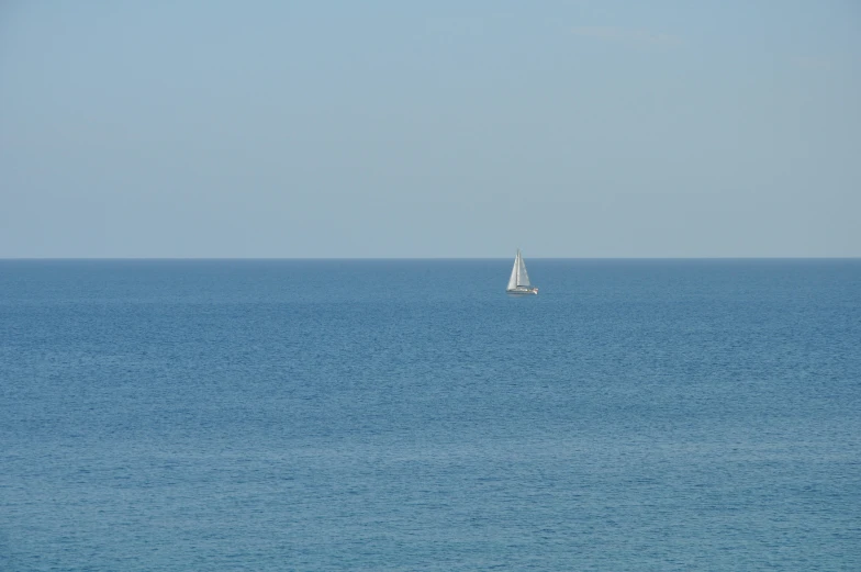 a sail boat out on the water near a beach
