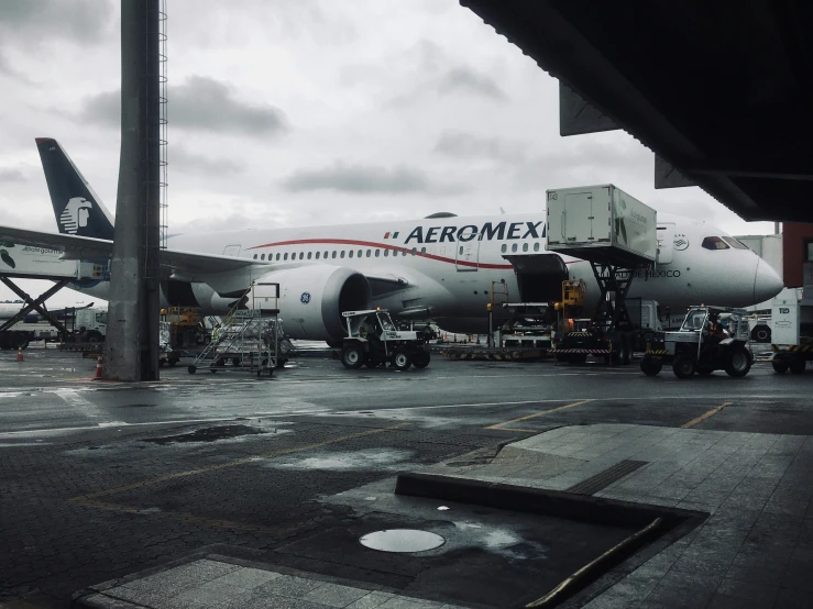 an airplane is parked on the tarmac under a cloudy sky