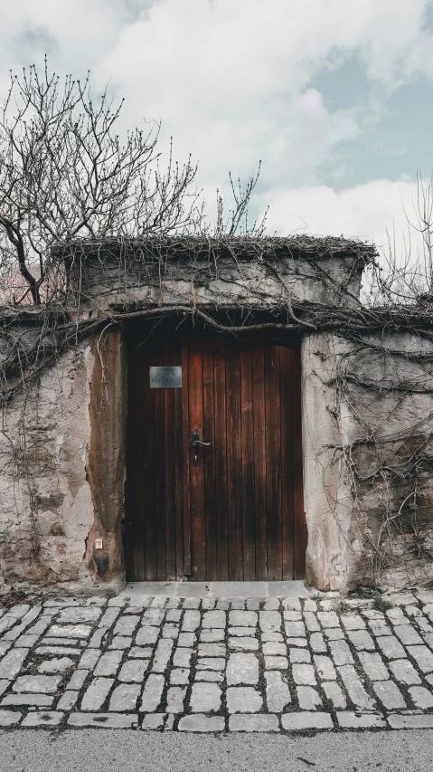 an old doorway with a wooden door on a brick street