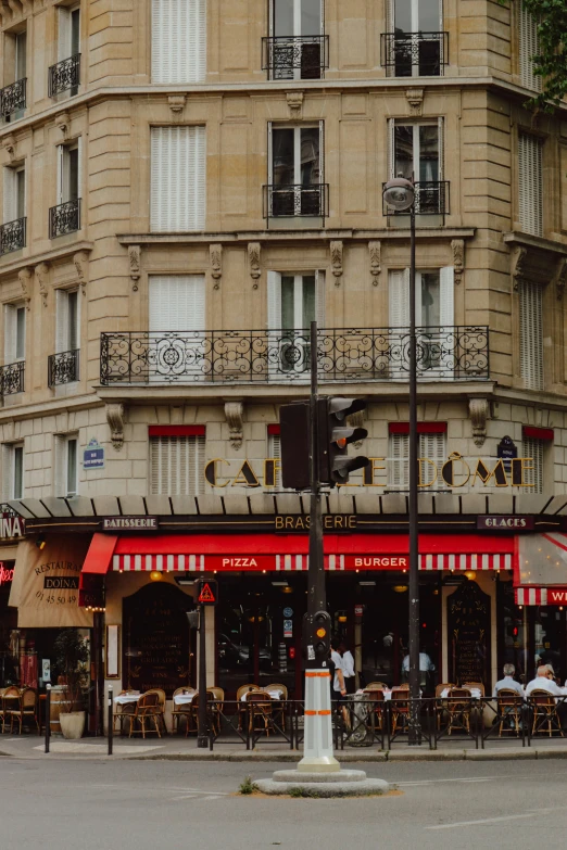 a corner of a sidewalk outside of a restaurant with a red and white awning