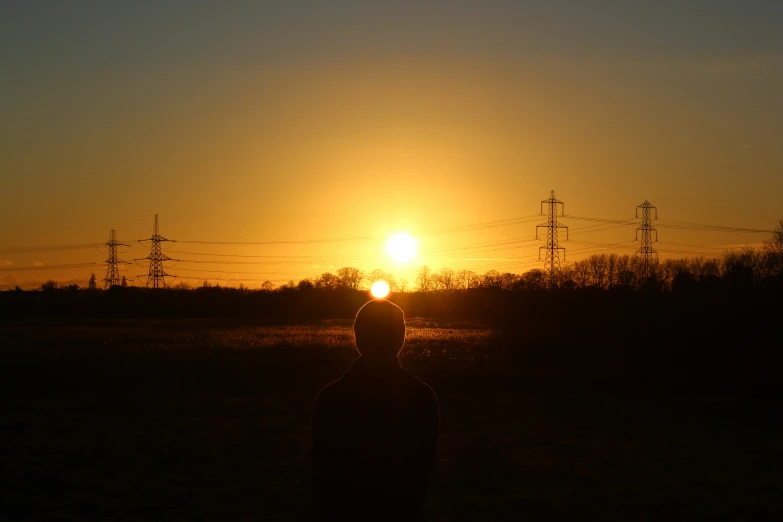 a man in a grassy field watching the sun set
