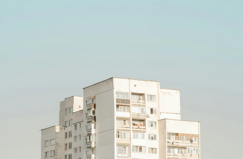 a tall white apartment building with balconies at the top of it