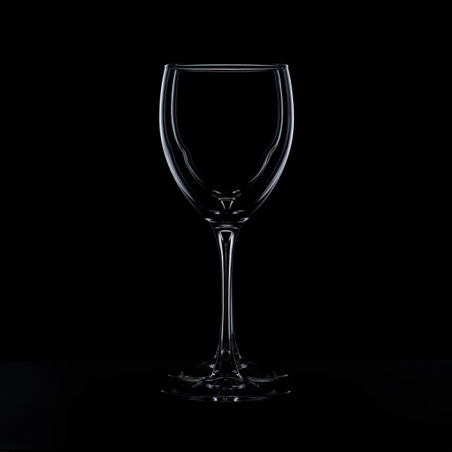 a single wine glass stands alone against a black background