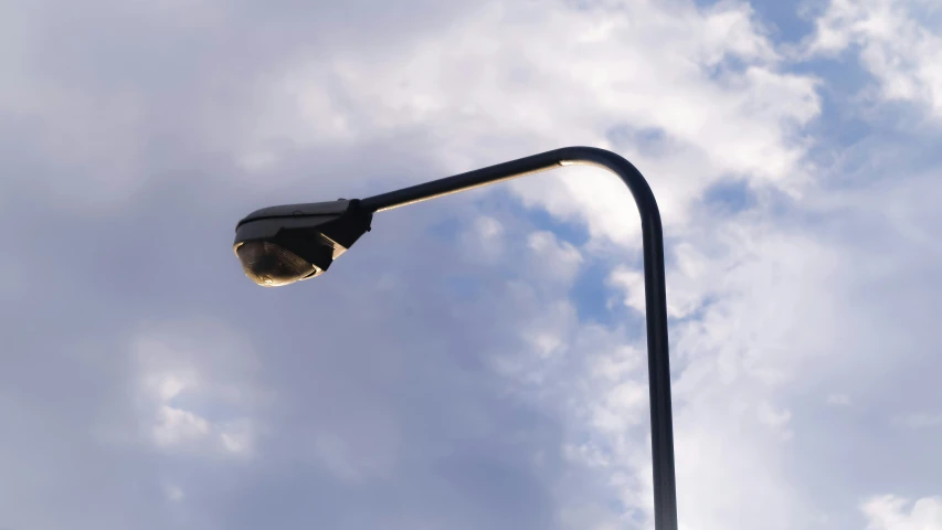 the street light is lit against the cloudy sky