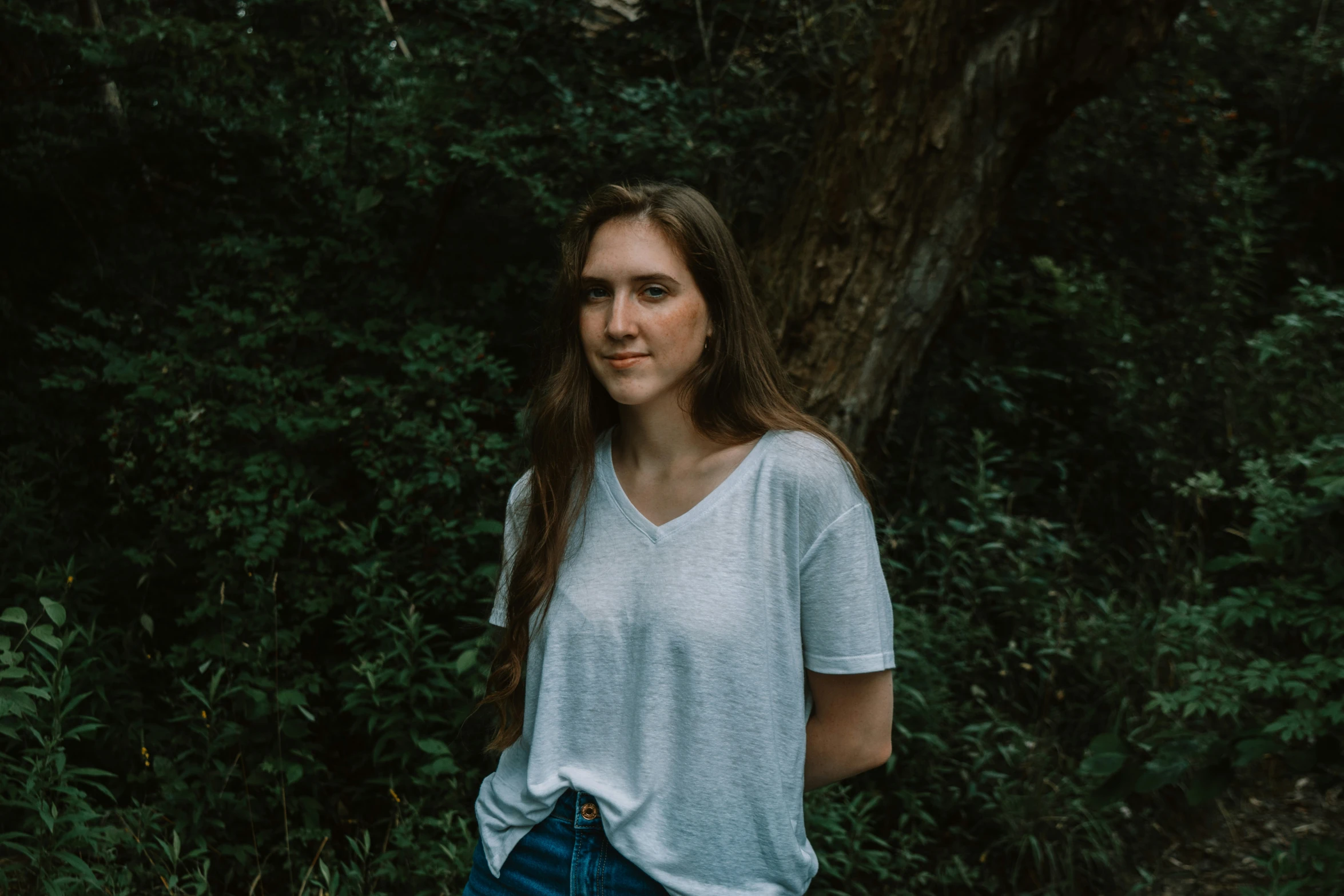 a beautiful young lady standing in a forest