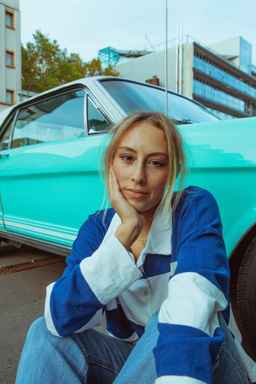 the girl poses in front of an old car