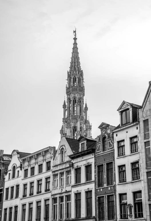 a tall tower rises high in the sky over many old buildings