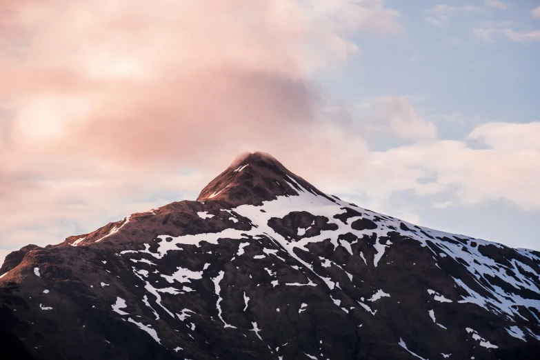 mountain covered in snow under cloudy blue sky