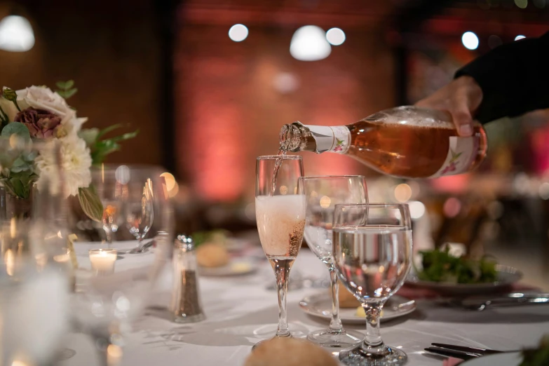 a person pouring wine into wine glasses at a table