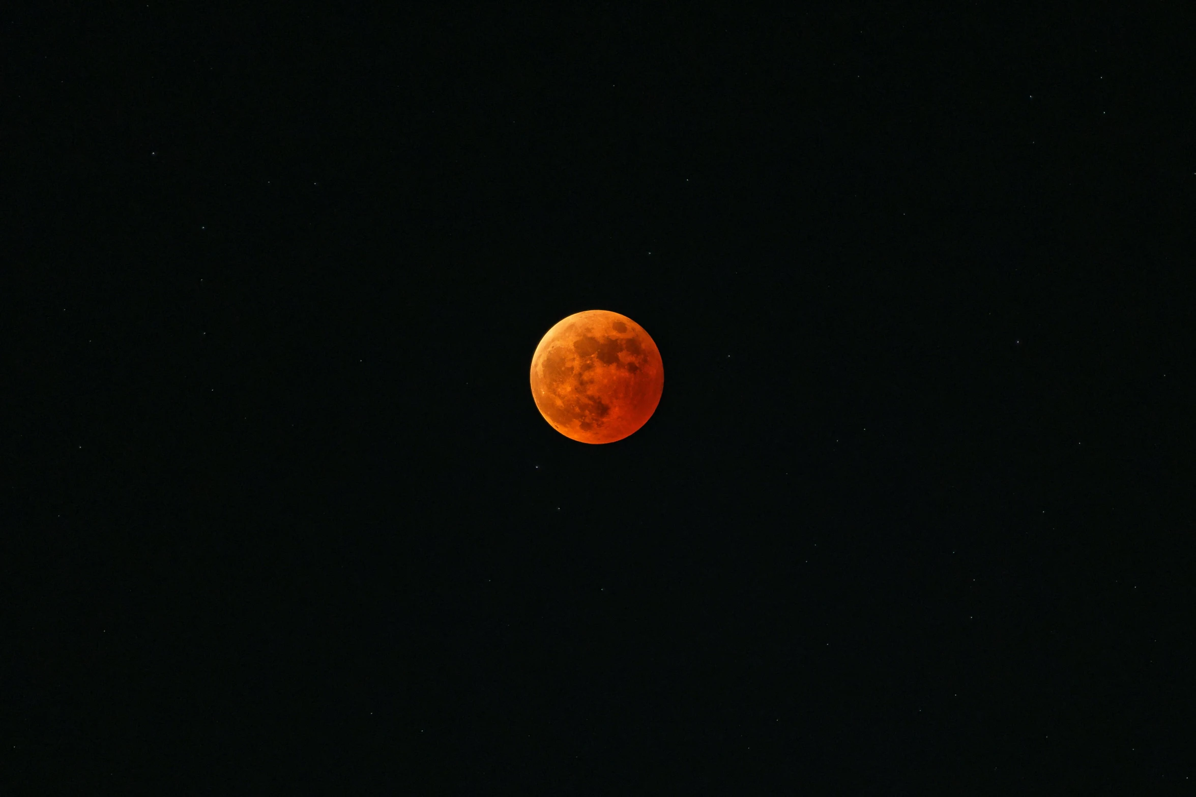 the moon is shining orange on the black sky