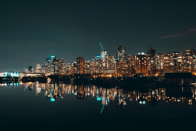 a city skyline at night, with a reflection in the water