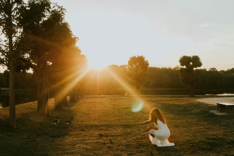 a woman is in the grass at sunset