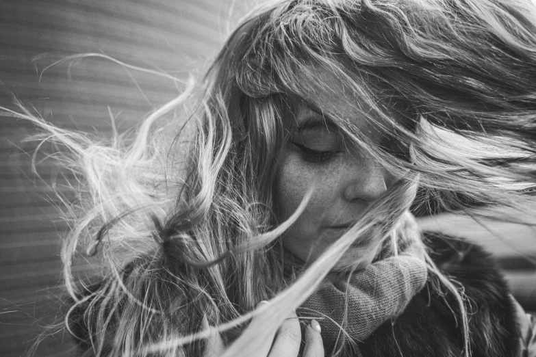 a woman blows her hair while she looks down