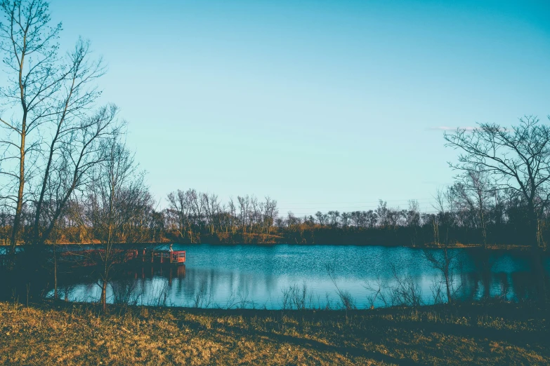 a beautiful still lake surrounded by trees in the late fall