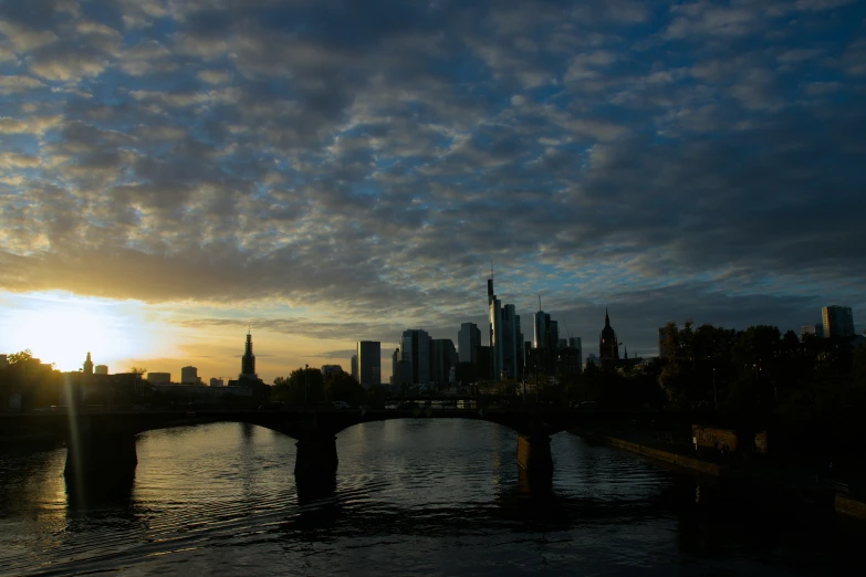 the sun setting behind a city skyline in the middle of water