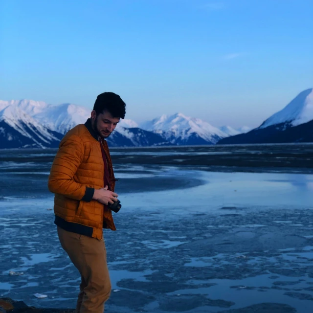 a man standing in front of mountains looking at his cellphone