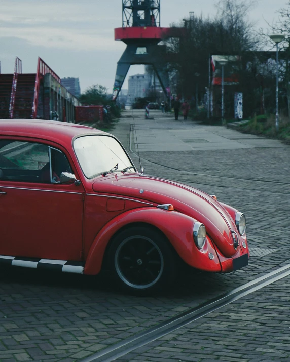 an old car with red paint sitting on the side of the road