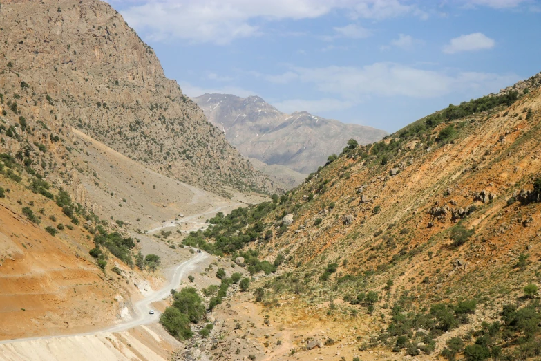 several cars driving down the road between mountains