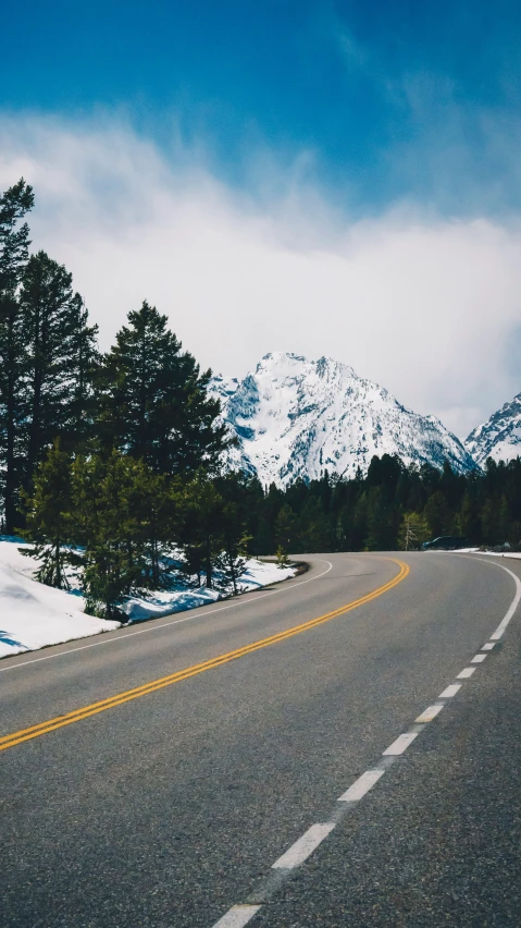 a road with a snow covered mountains on both sides