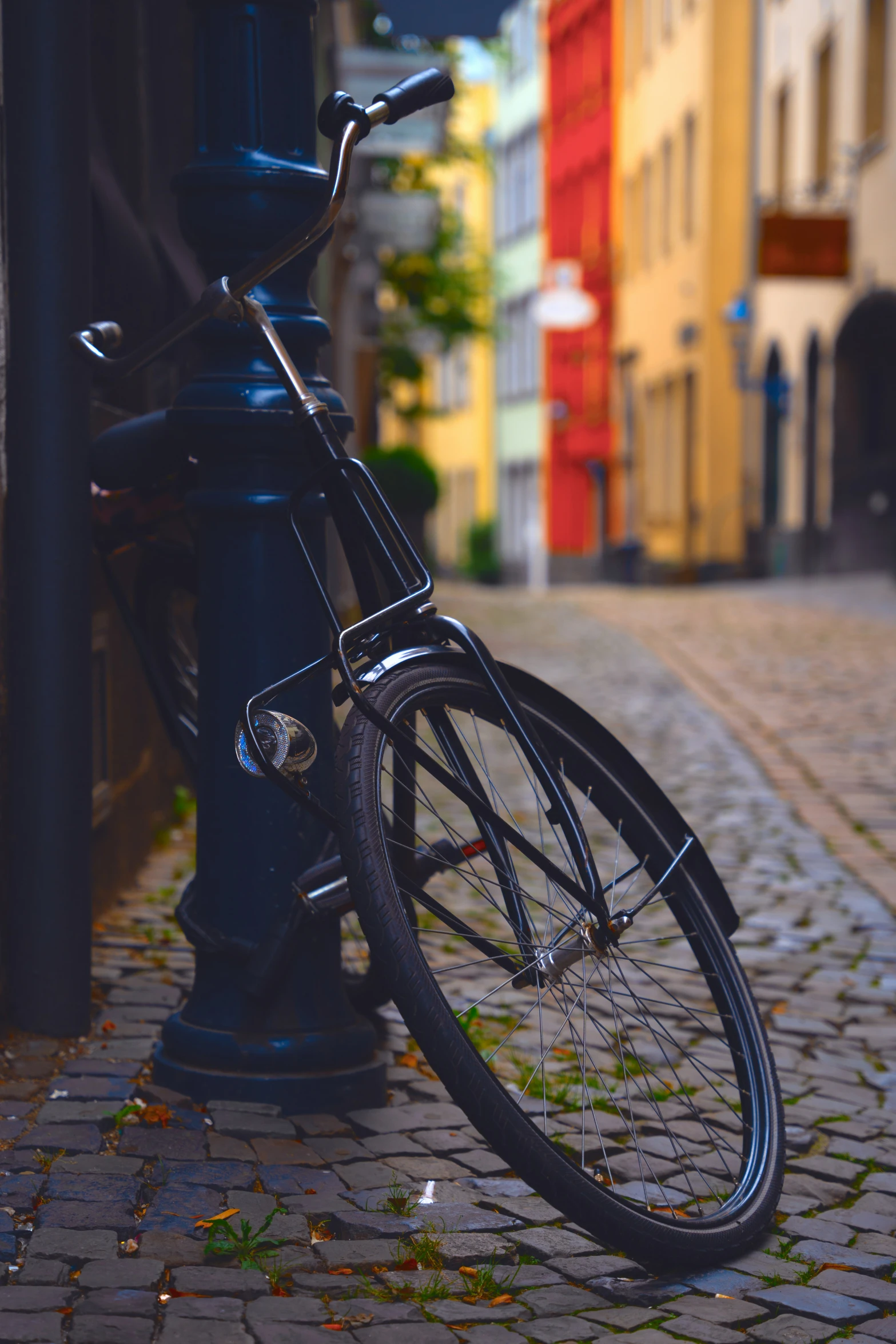 bicycle locked to post on street with buildings in background