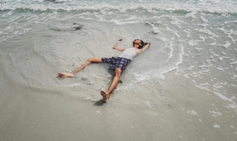 a man laying on the beach near the ocean