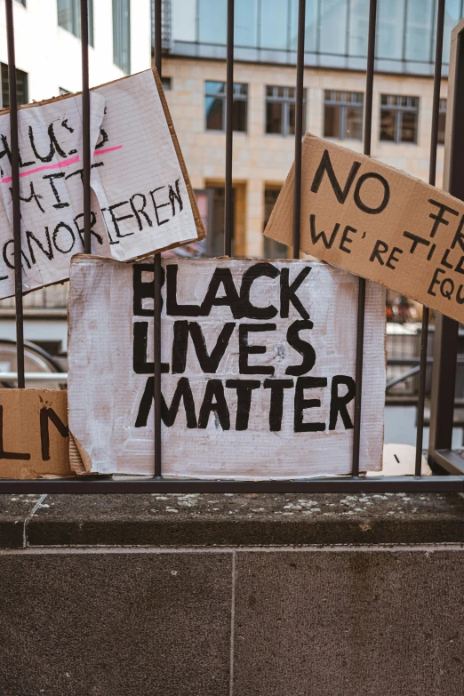 a set of protest signs behind bars in front of some buildings