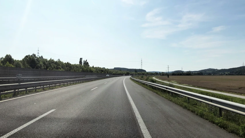 an empty road in the middle of a grassy field