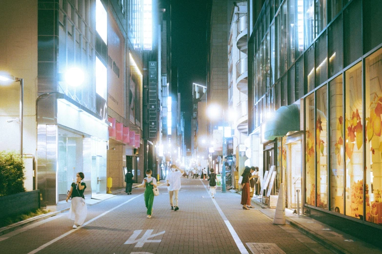 people are walking down a city street at night