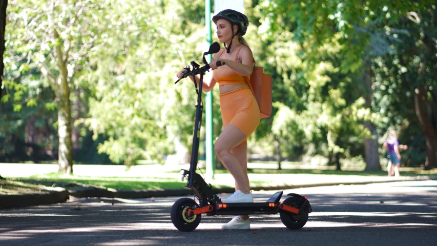 a young woman wearing orange skirt and pink boots rides an electric scooter