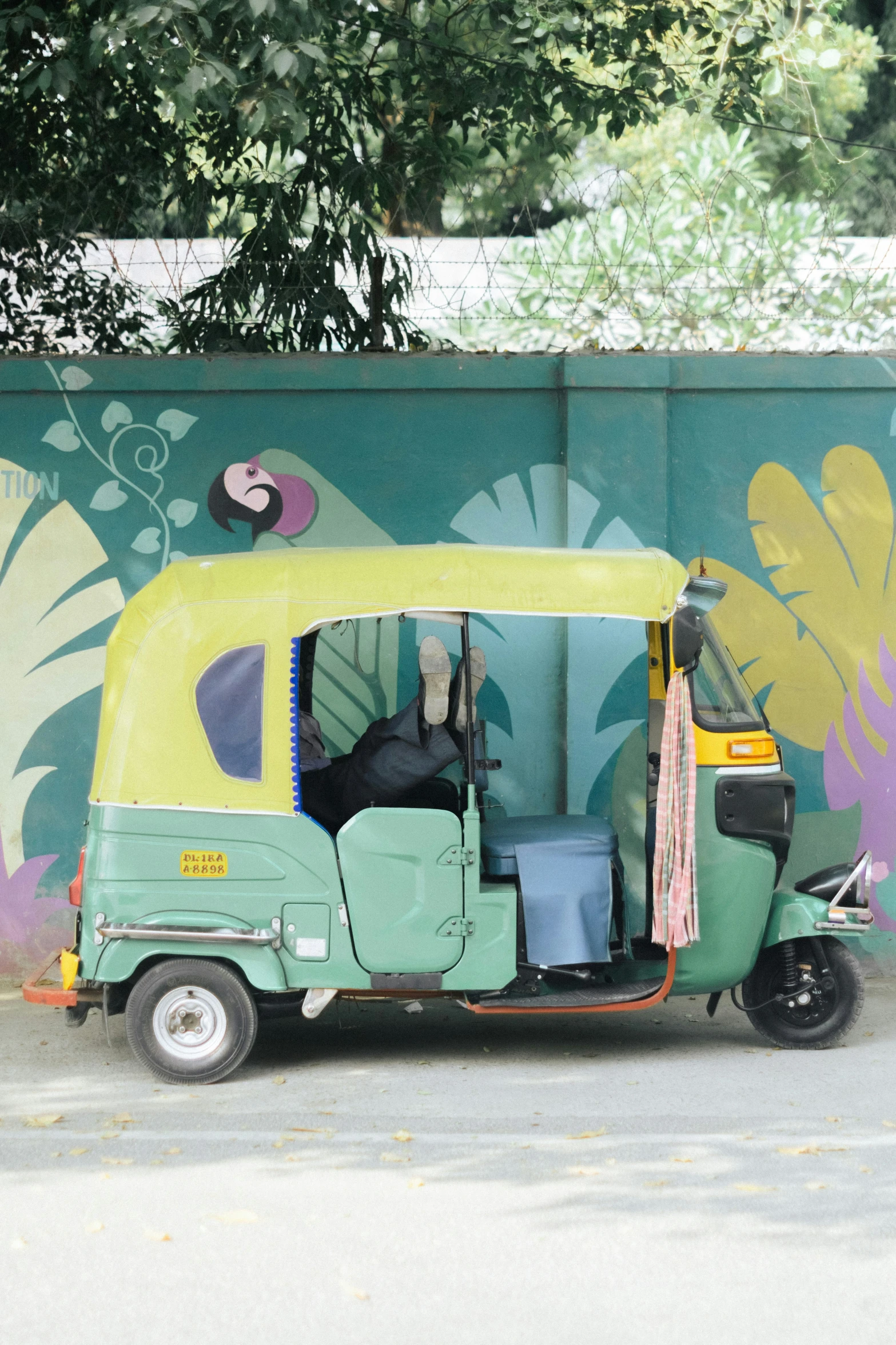 green motor vehicle with colorful mural on side of building