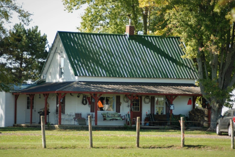 a small white and green house sits in a field