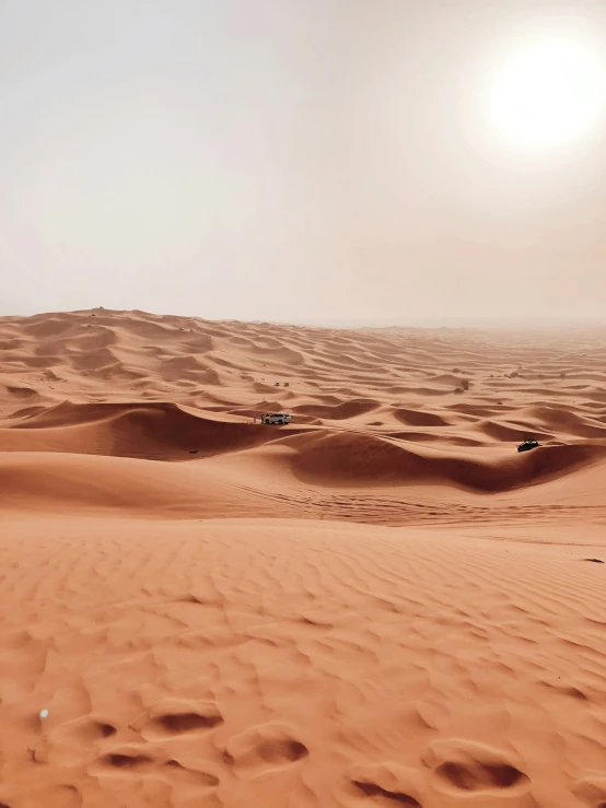 a dune - covered landscape with cars parked in the distance