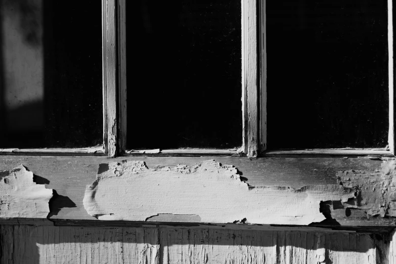 an old bench with two open windows in the background