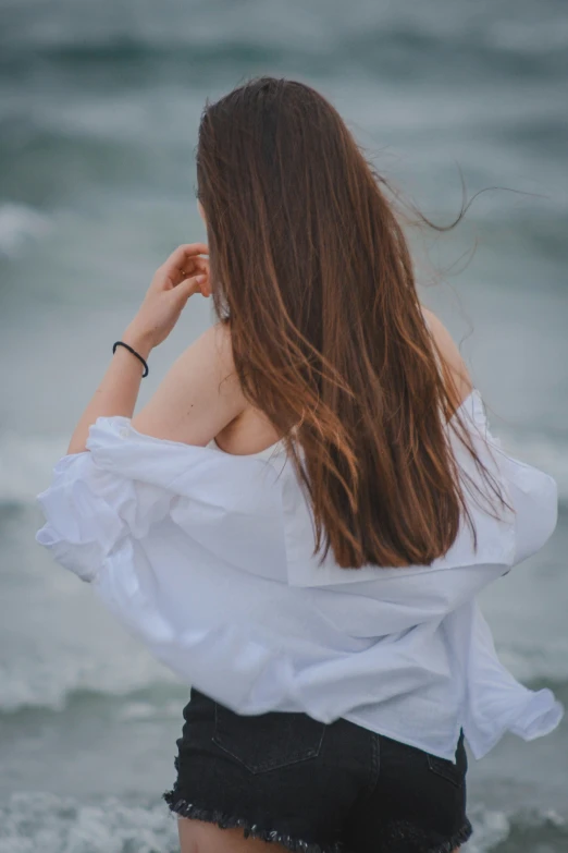 a woman in a white shirt and black shorts standing in the ocean