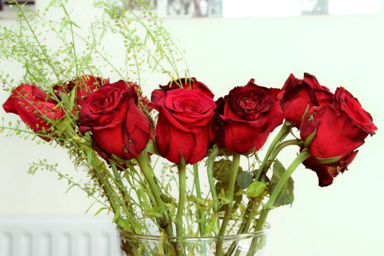 a bunch of red roses sitting in a vase on a table