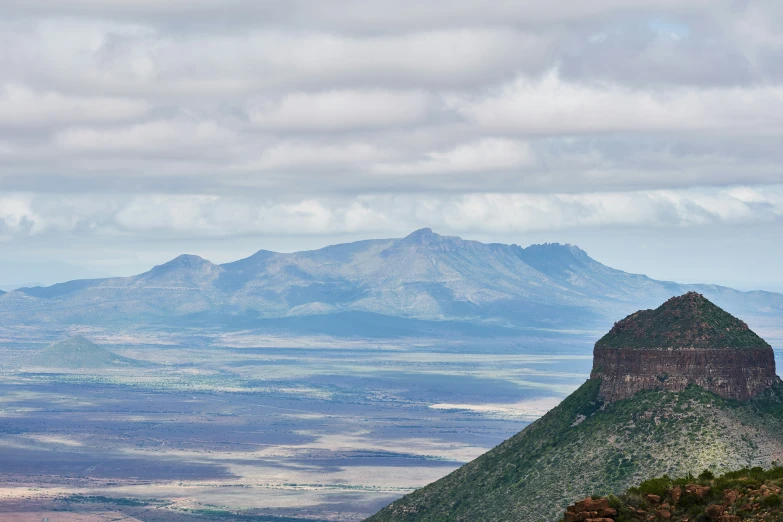 the view from a hill top looking down on a valley and mountains