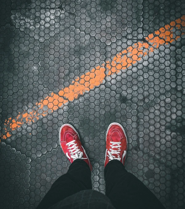 a pair of red sneakers standing on a pavement