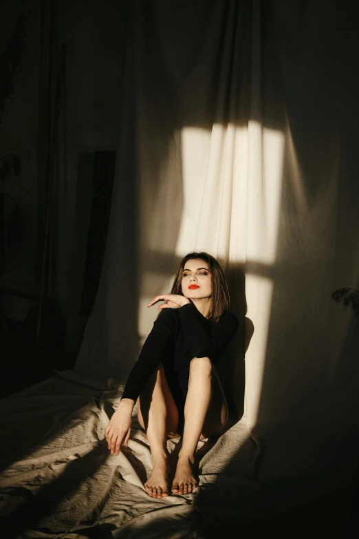woman sitting on bed with sun streaming through her window