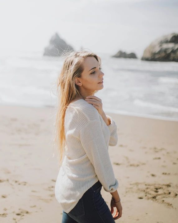 a girl in a white top standing on a beach