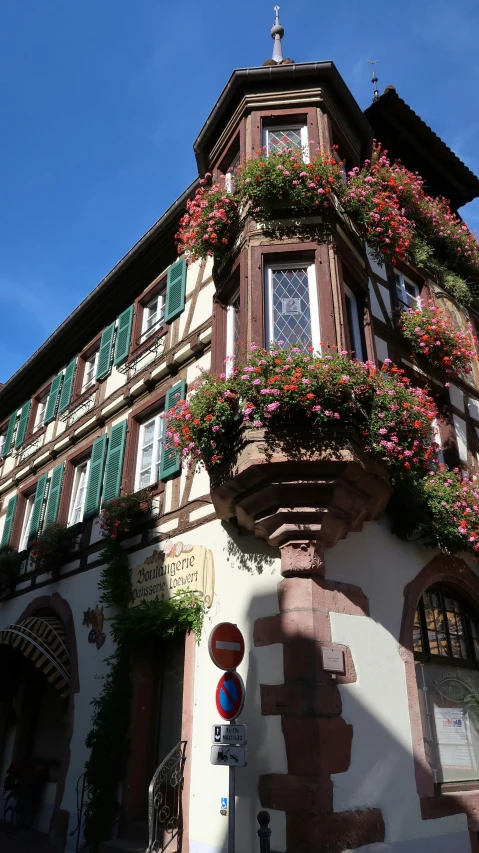 the side of an old building has green shutters and flowers on the windows