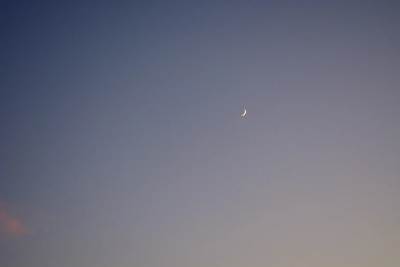 the moon is visible in the clear blue sky