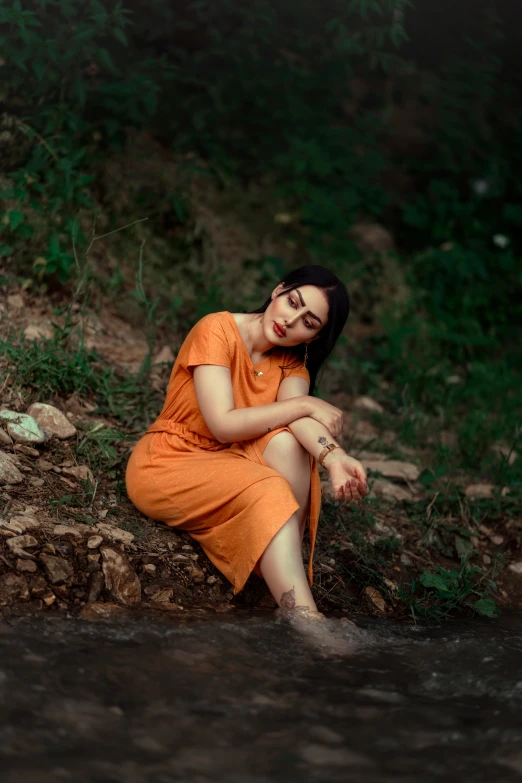 a young lady is sitting on the shore near water