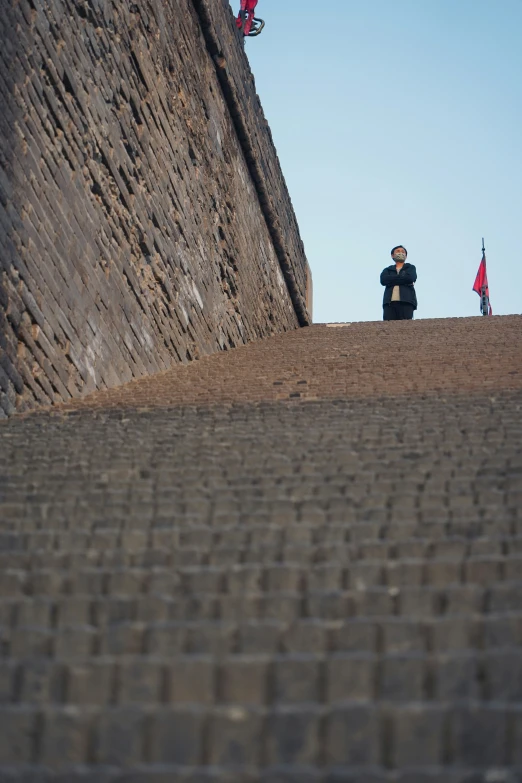 the person is sitting on a brick wall taking pictures