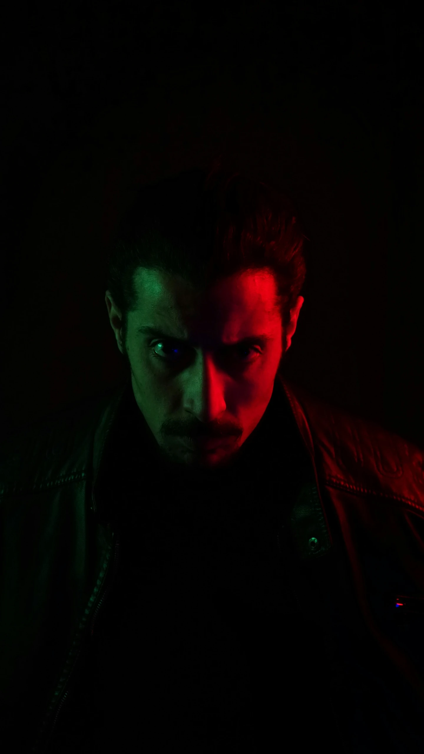 a man standing in a dark room with his head slightly turned towards the camera