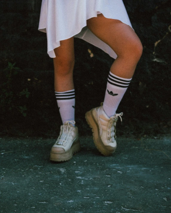 a woman in white clothing is standing with her legs crossed