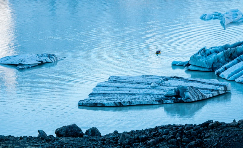 a man kayaks on an icy river in the wilderness