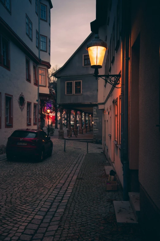 a small street at dusk with a car parked next to it