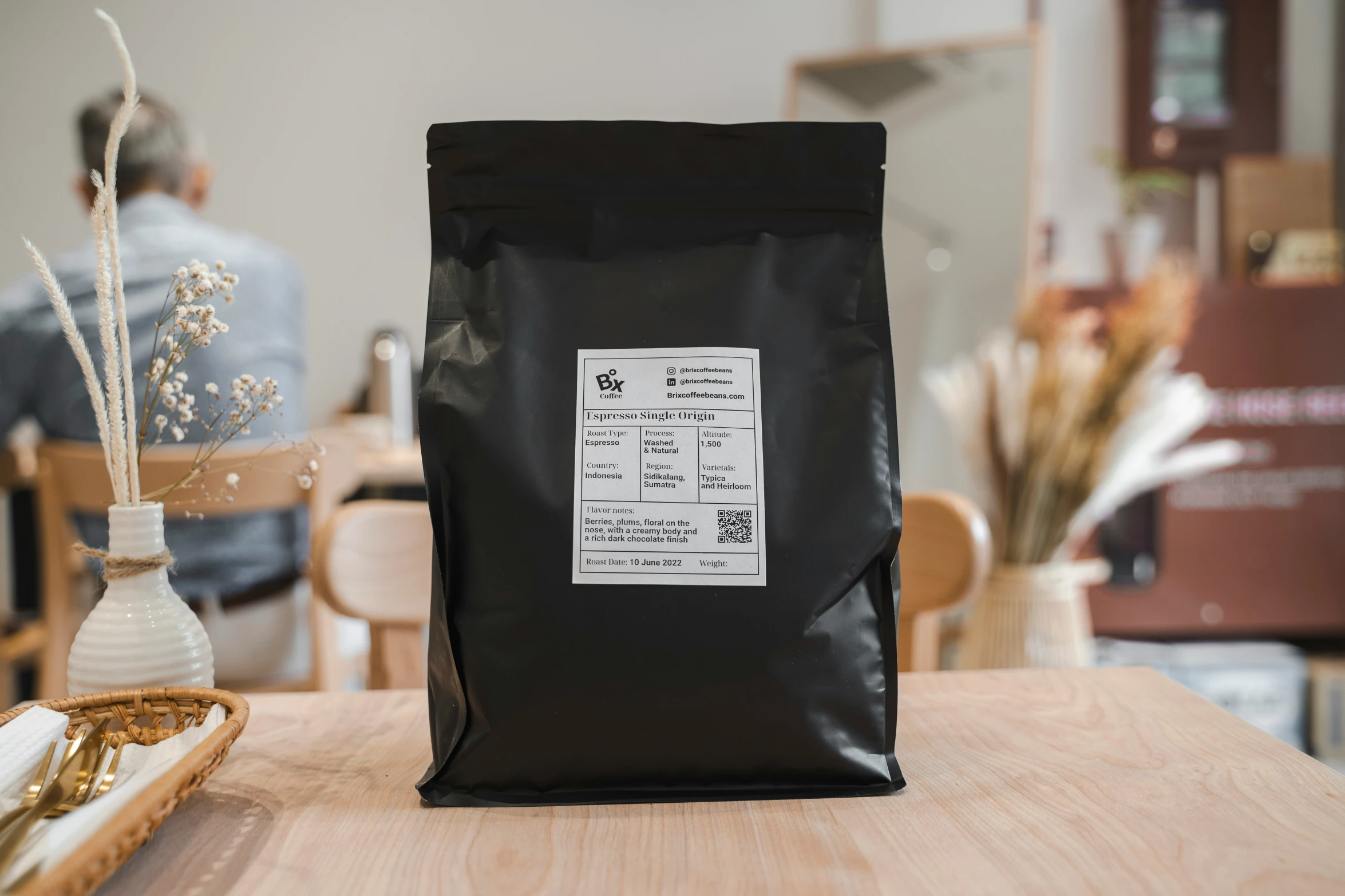 a coffee bag is sitting on the table near a vase and a plate