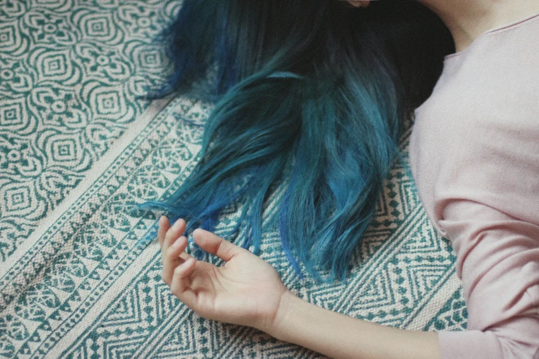 a woman with long, blue hair is sitting on the floor